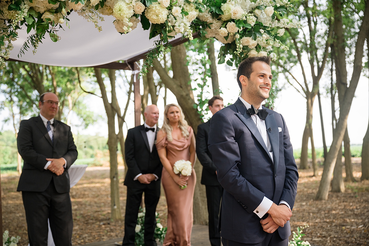 groom waits for bride at the end of the aisle