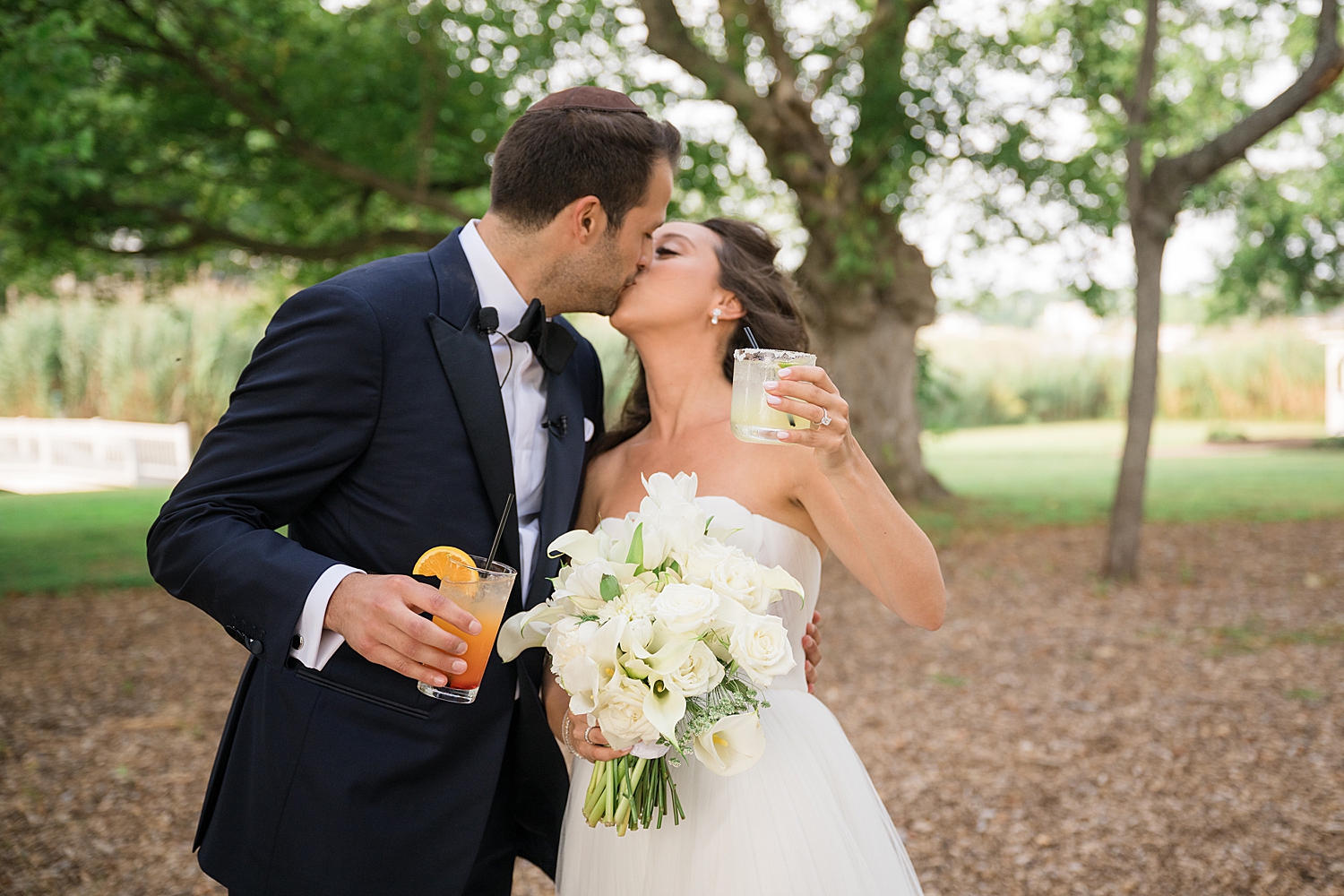 bride and groom kiss, holding signature drinks