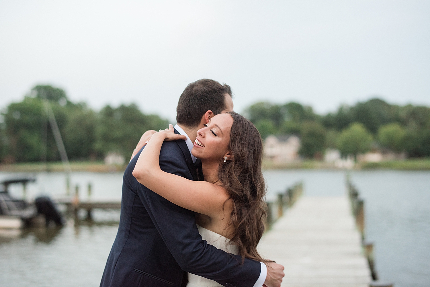 bride and groom hug on pier