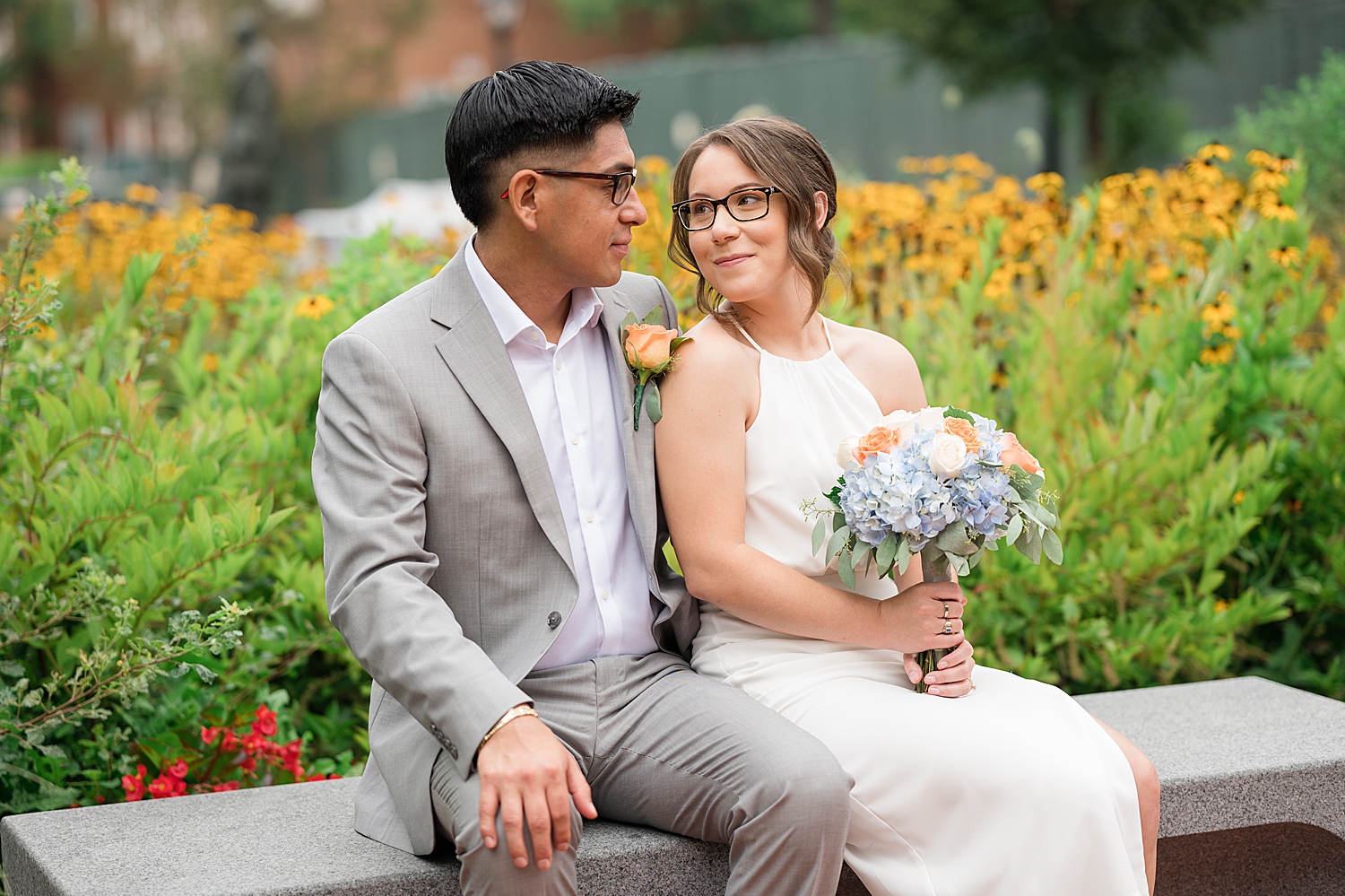 bride and groom sit on bench together