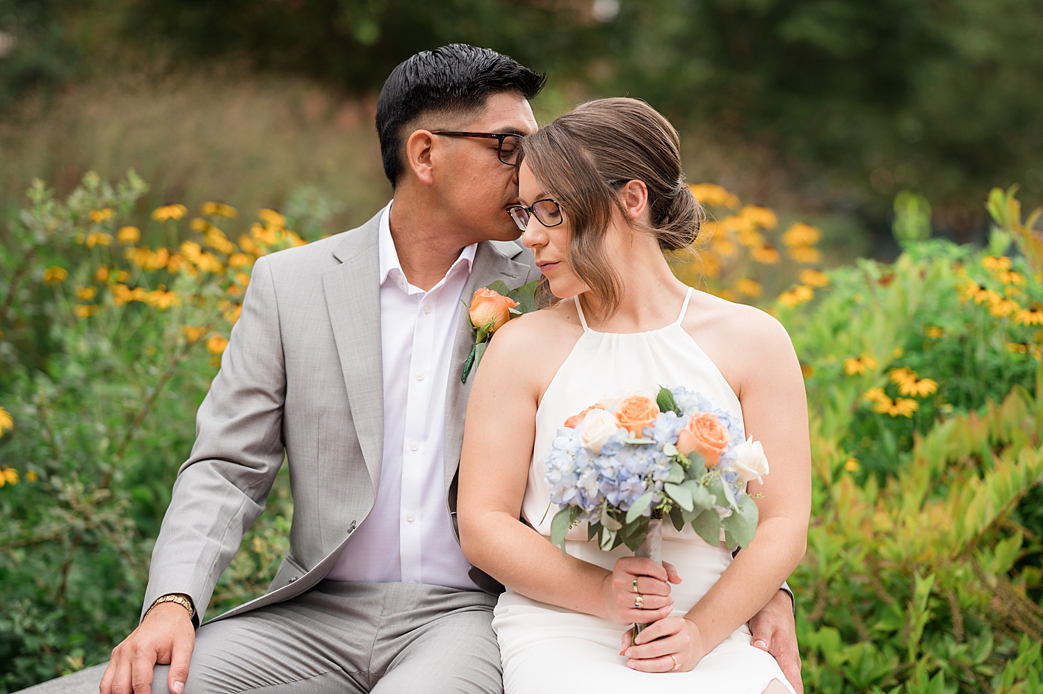 bride and groom sit on bench together