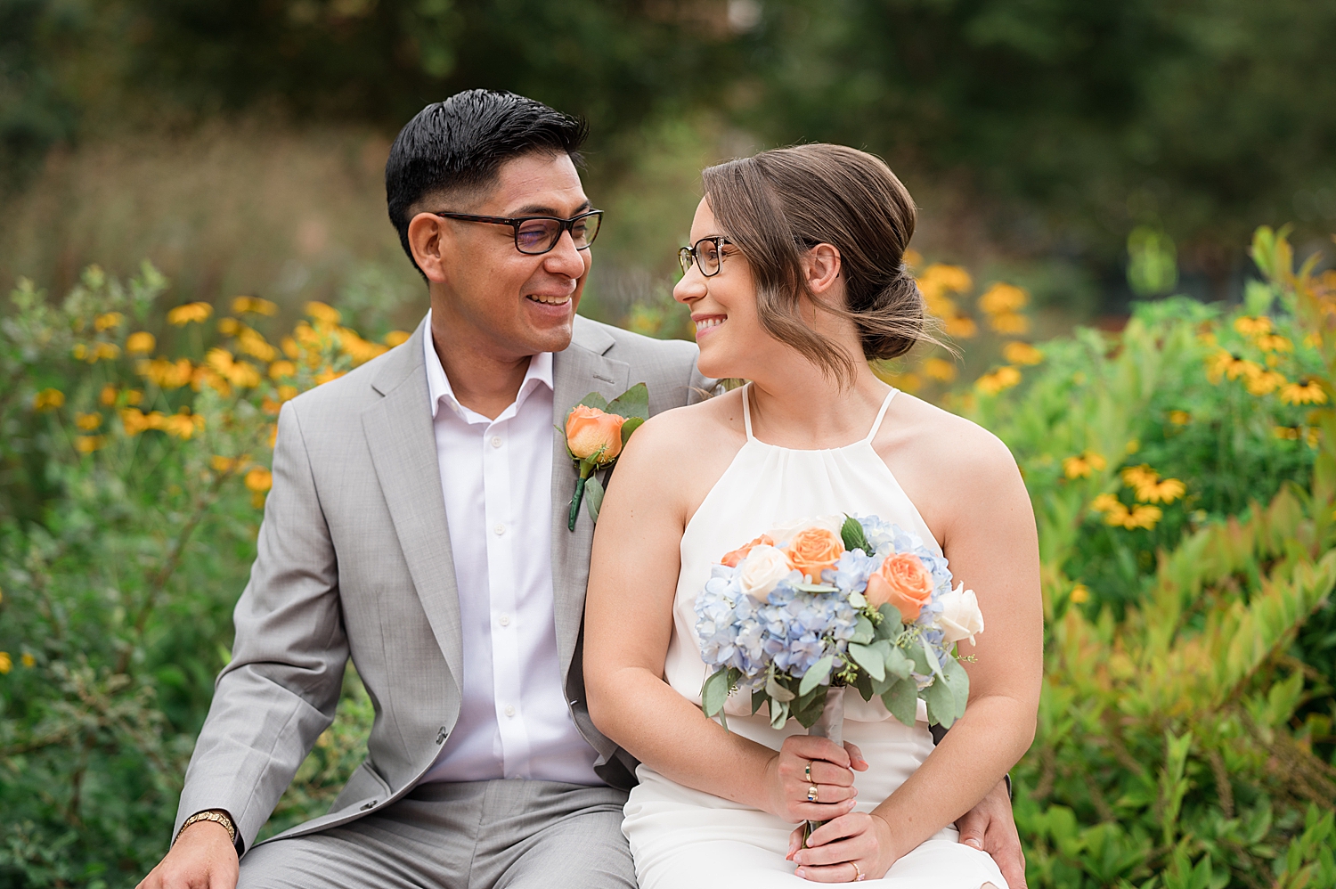 bride and groom sit on bench together