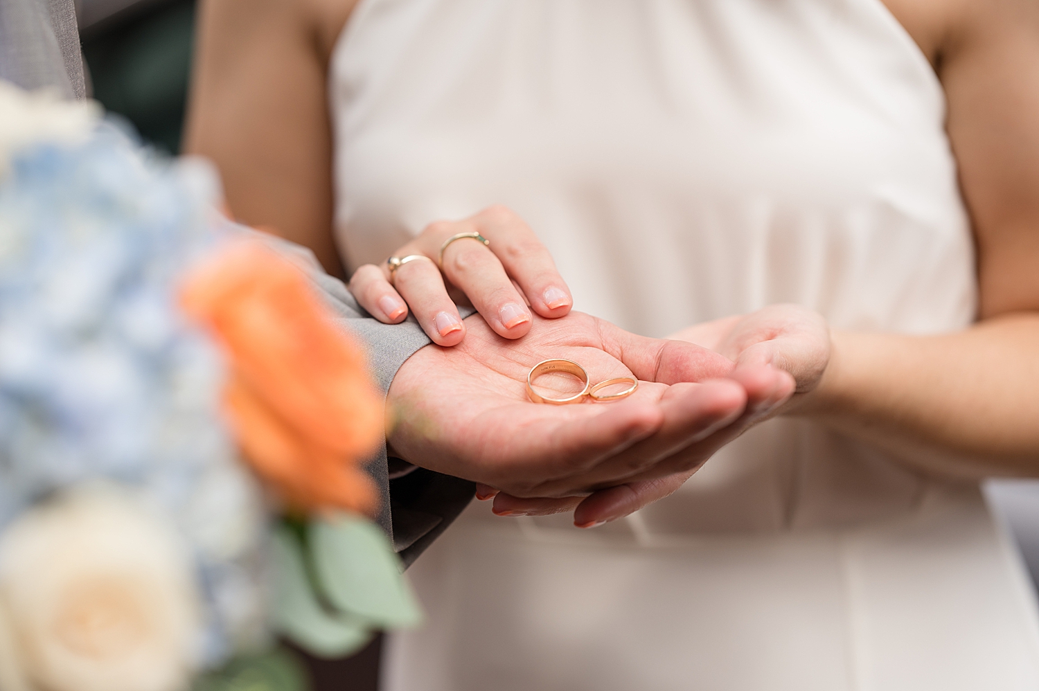 bride and groom hold wedding rings