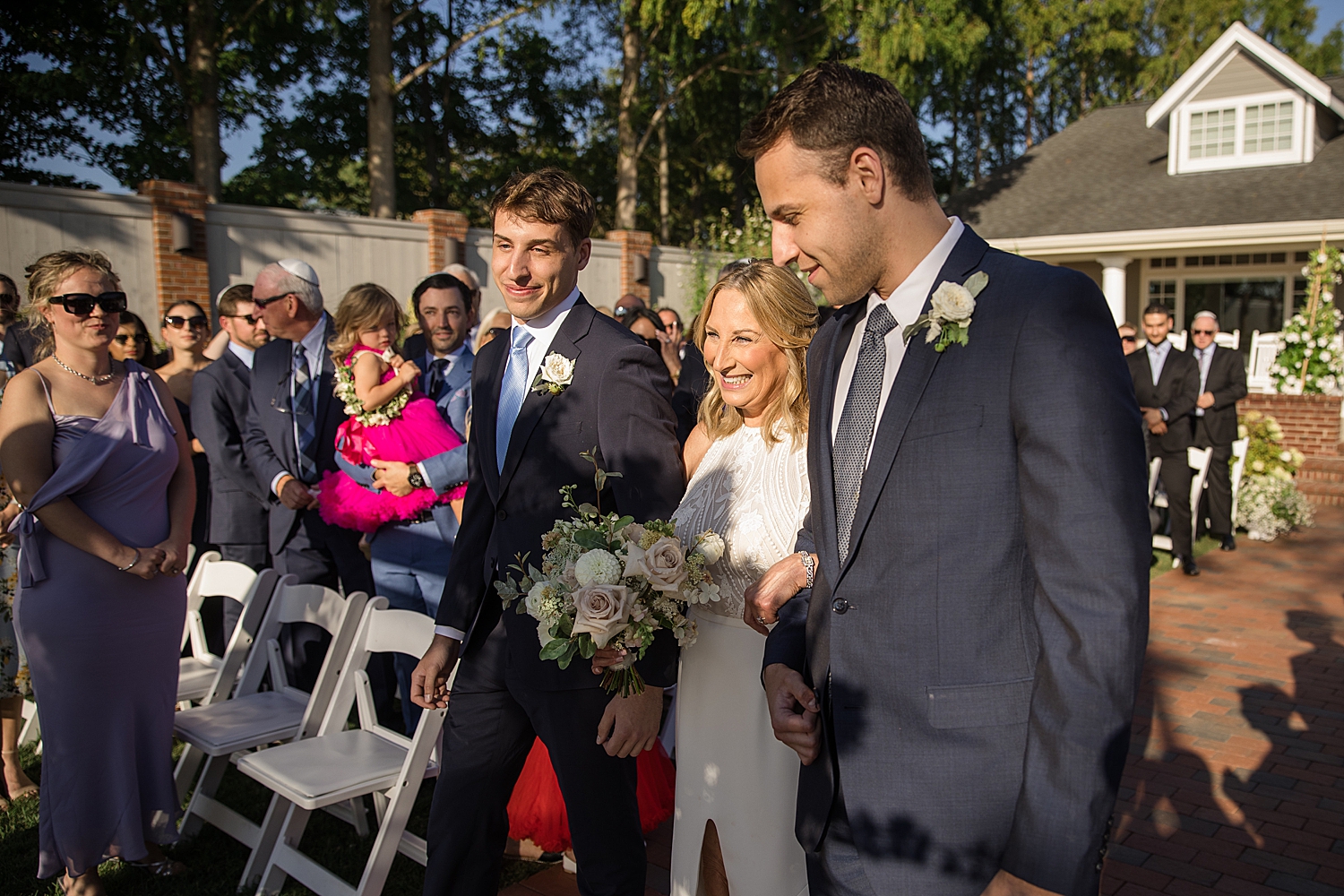 bride arrives at ceremony, escorted by sons