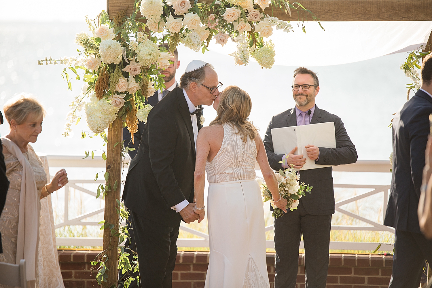 bride and groom outdoor ceremony under white floral arch