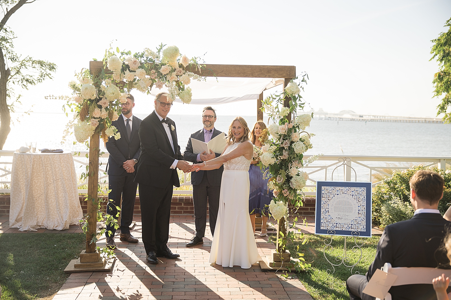 bride and groom outdoor ceremony under white floral arch