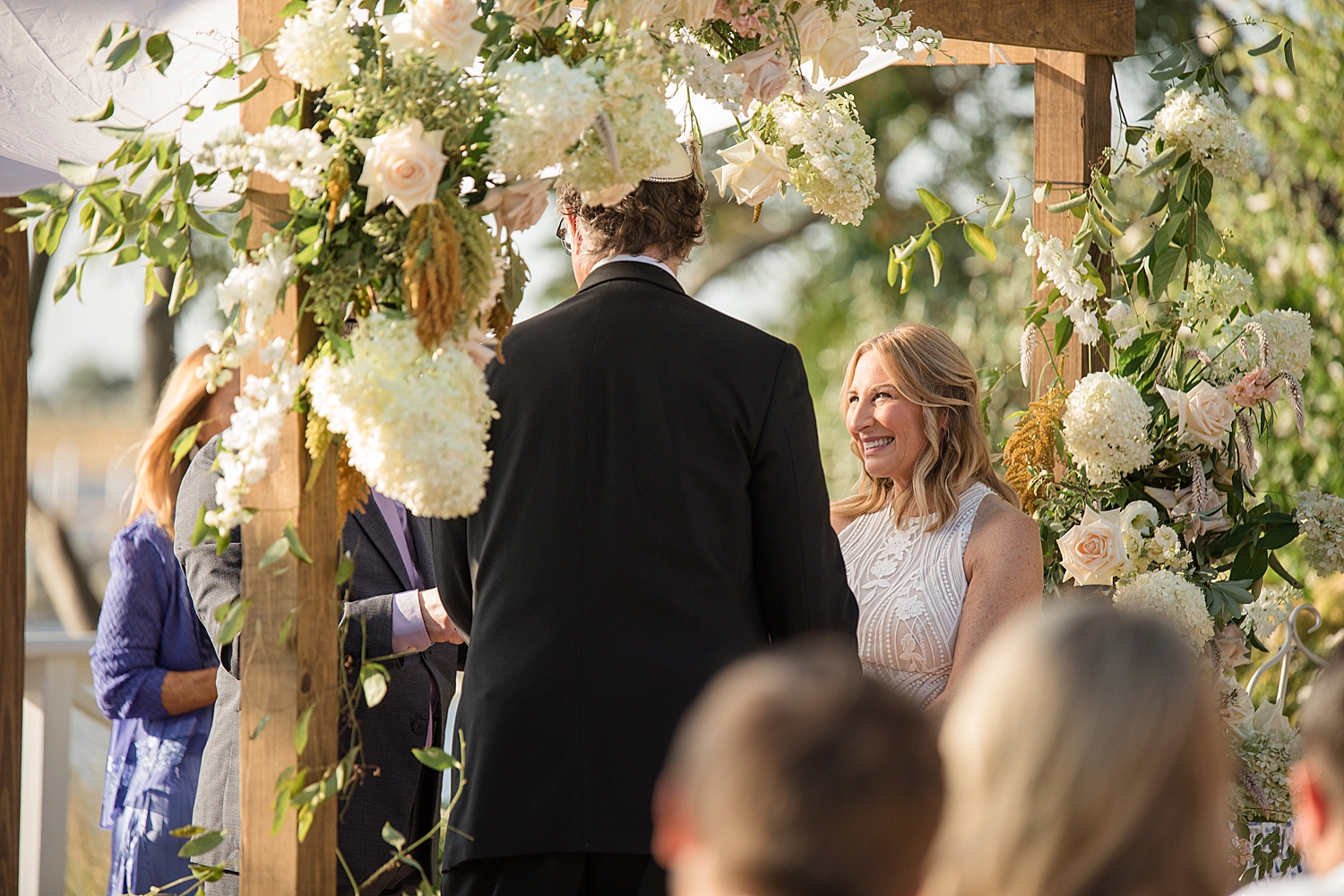 bride and groom outdoor ceremony under white floral arch