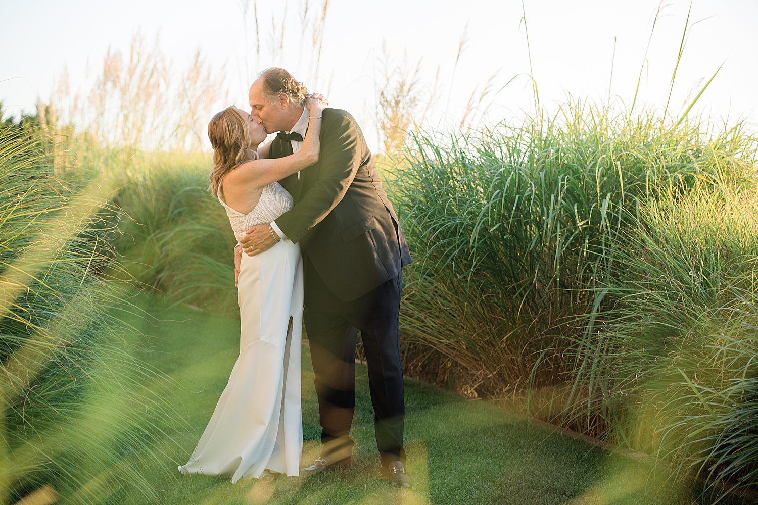 bride and groom kiss in grass