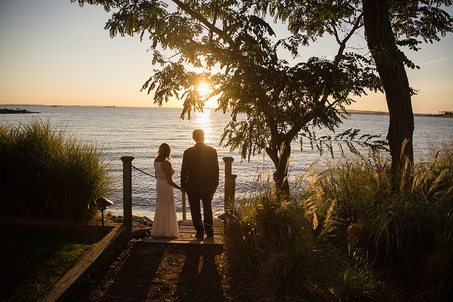 bride and groom silhouetted against sky during sunset on chesapeake bay