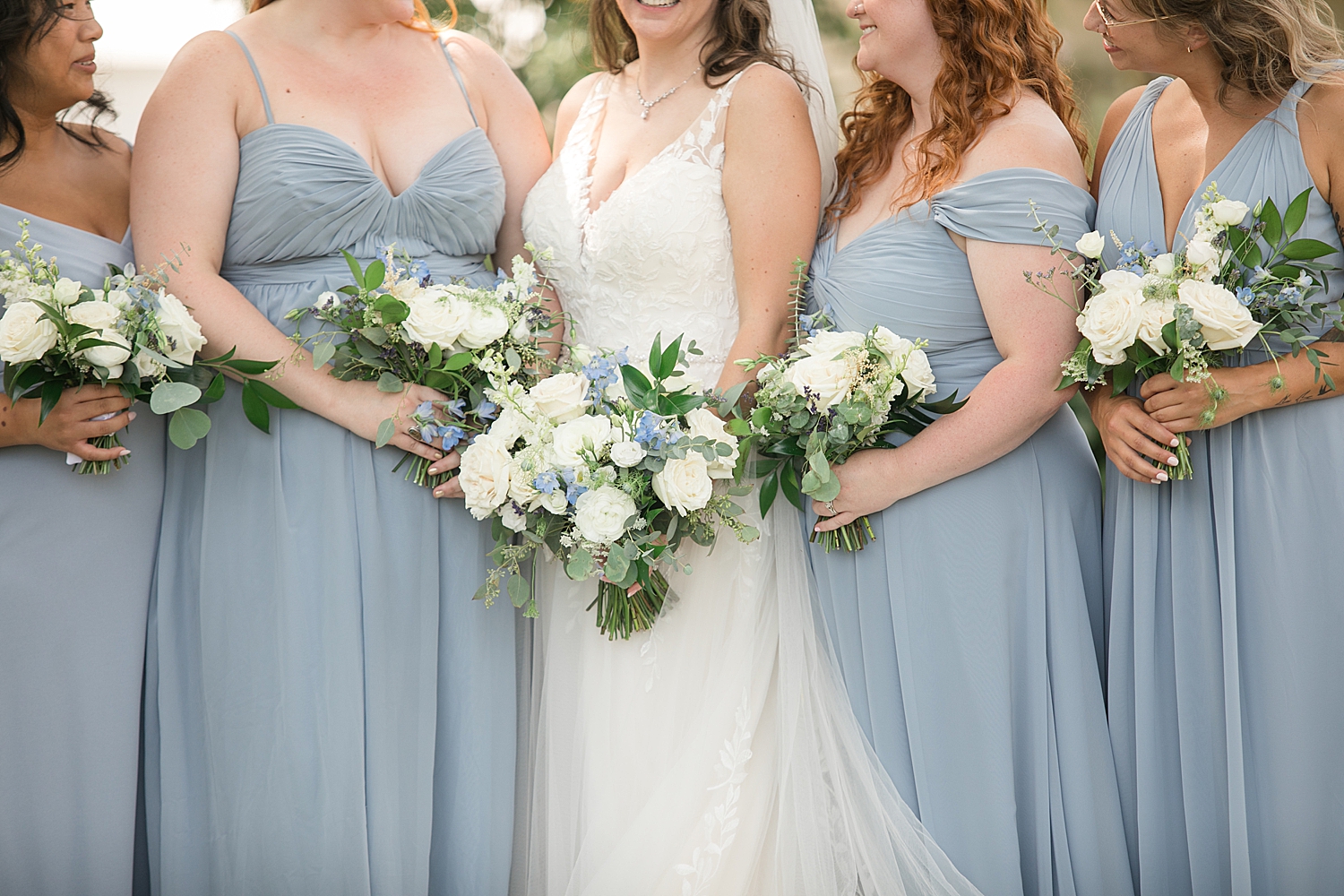 close up of bridesmaids' white bouquets against dusty blue dresses