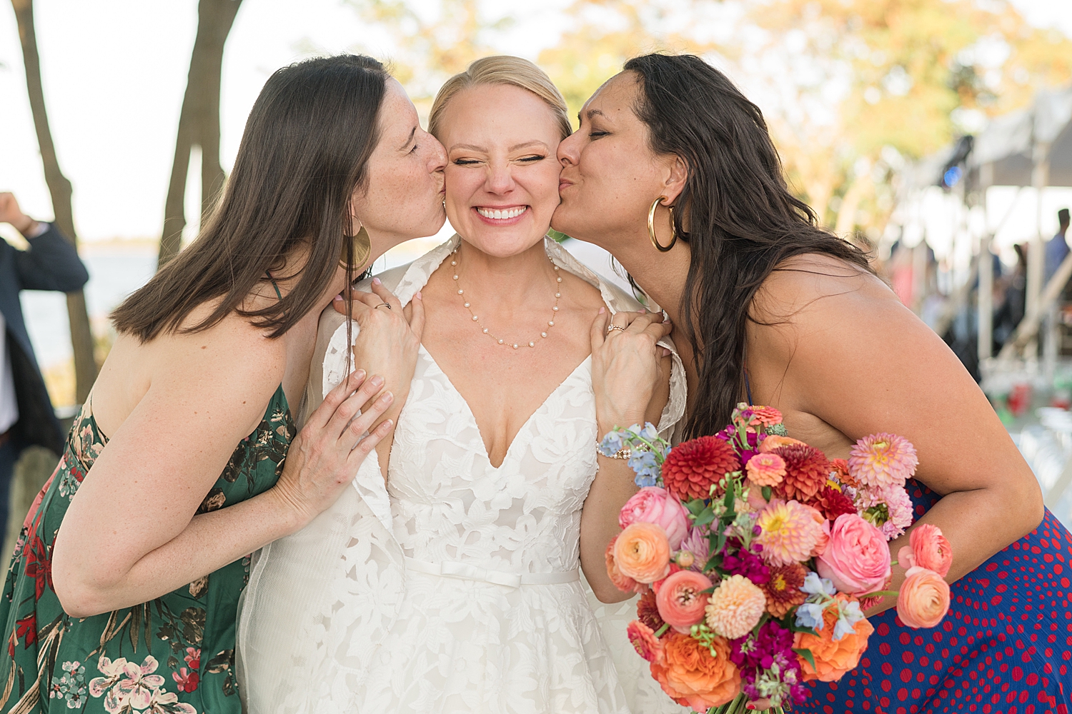 two guests kiss bride's cheeks on either side