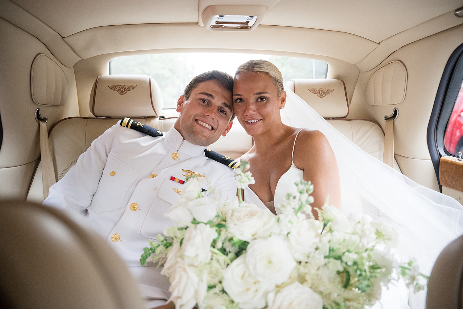 bride and groom smile in back of limo