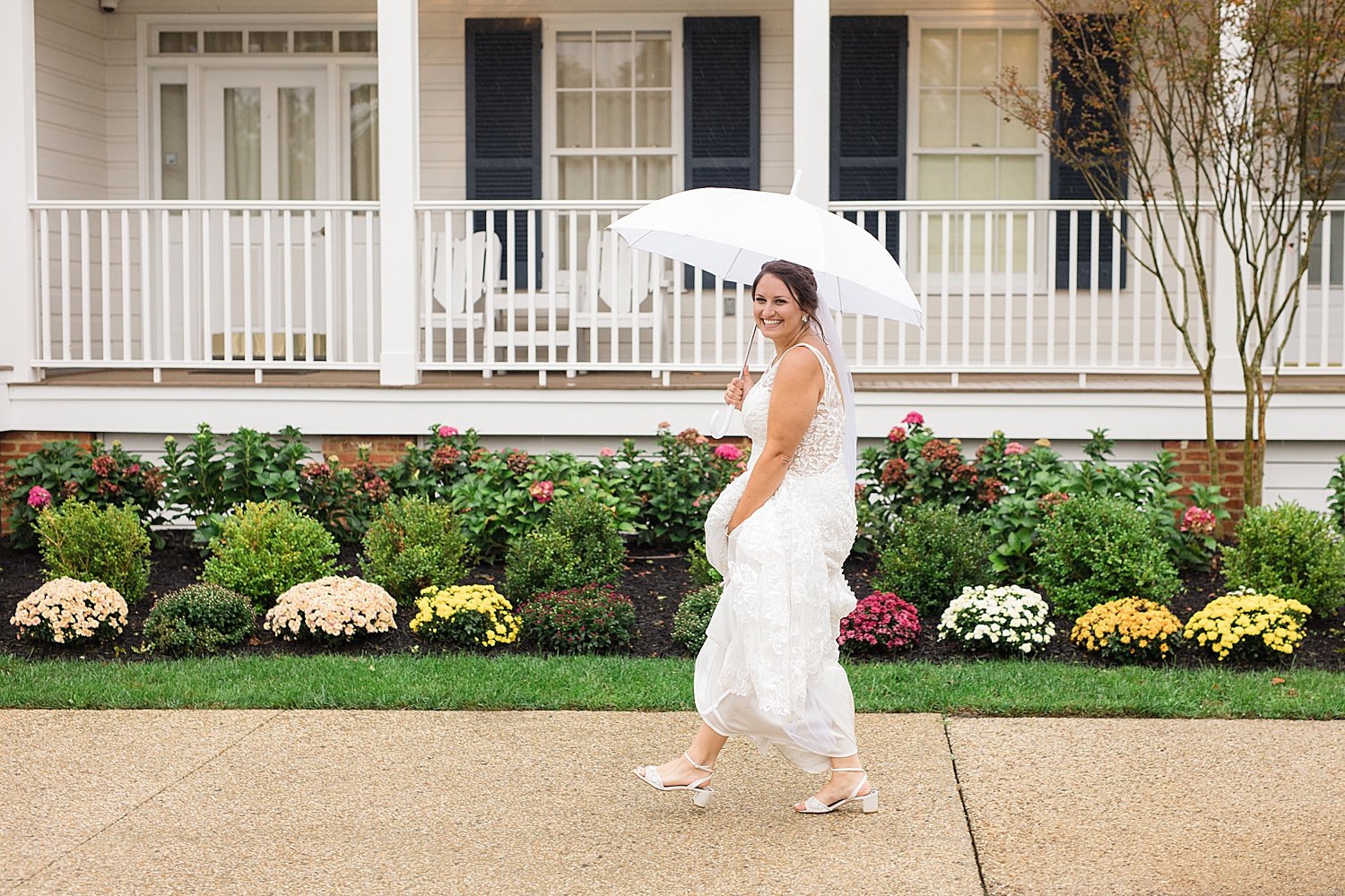 brides walks through the rain holding umbrella