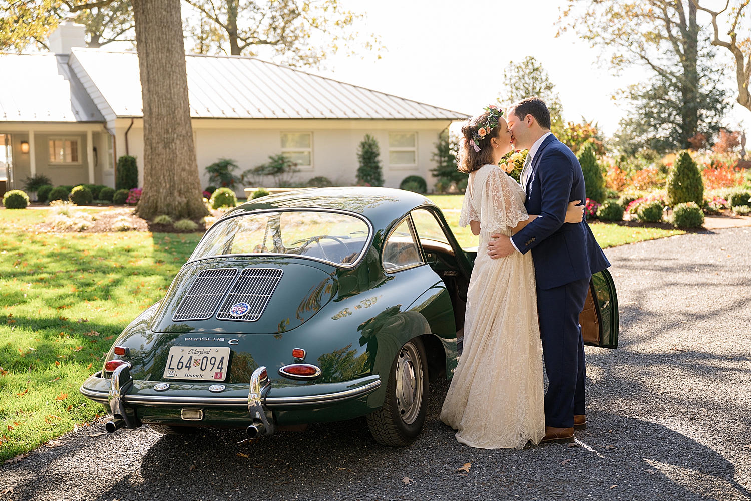 bride and groom kiss in front of green vintage car