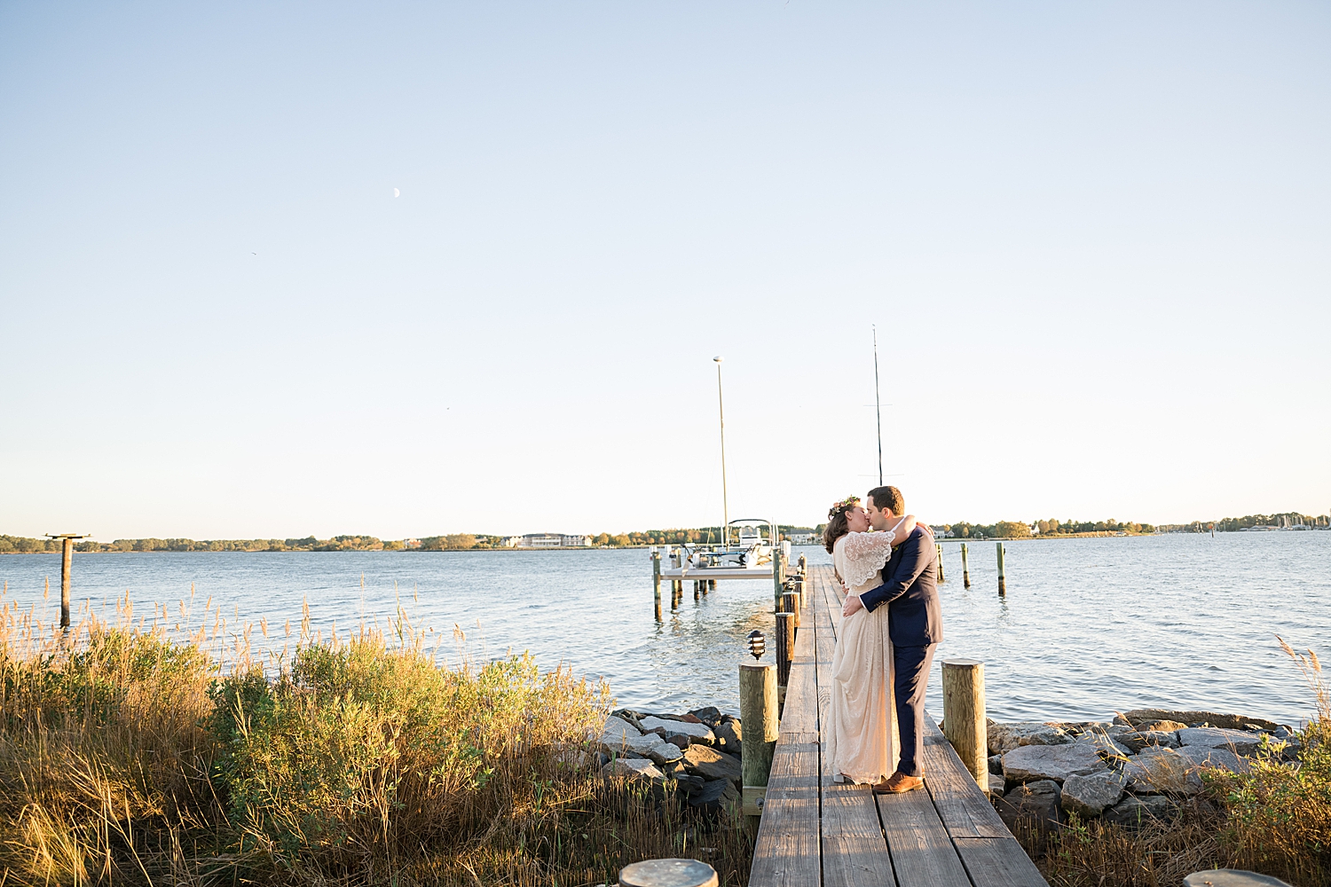 bride and groom kiss on pier