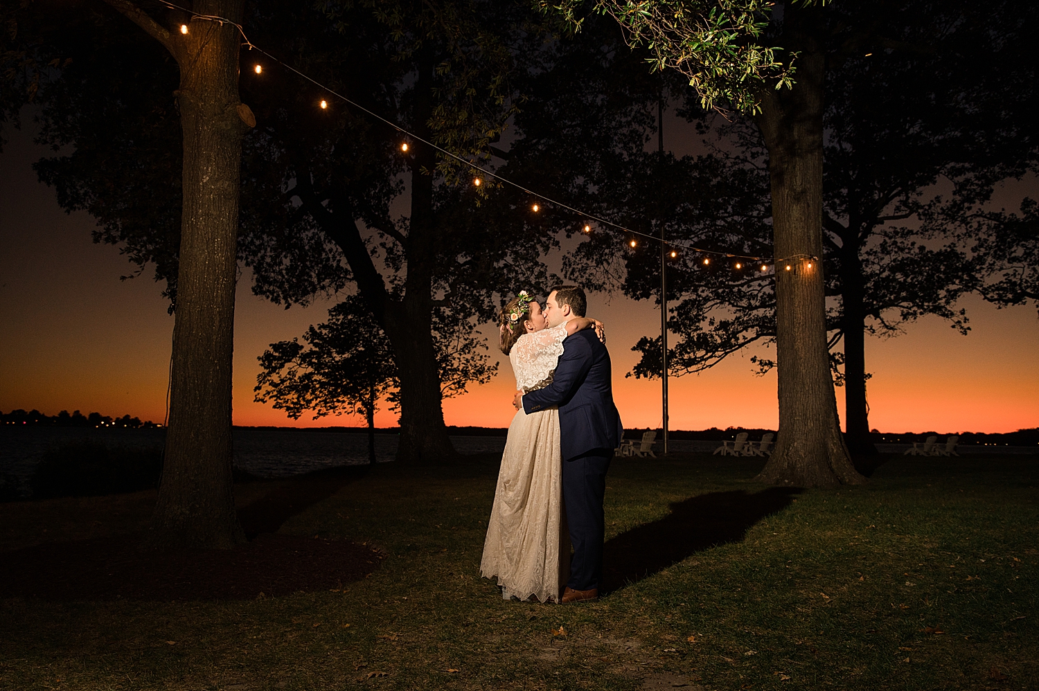 bride and groom kiss under string lights