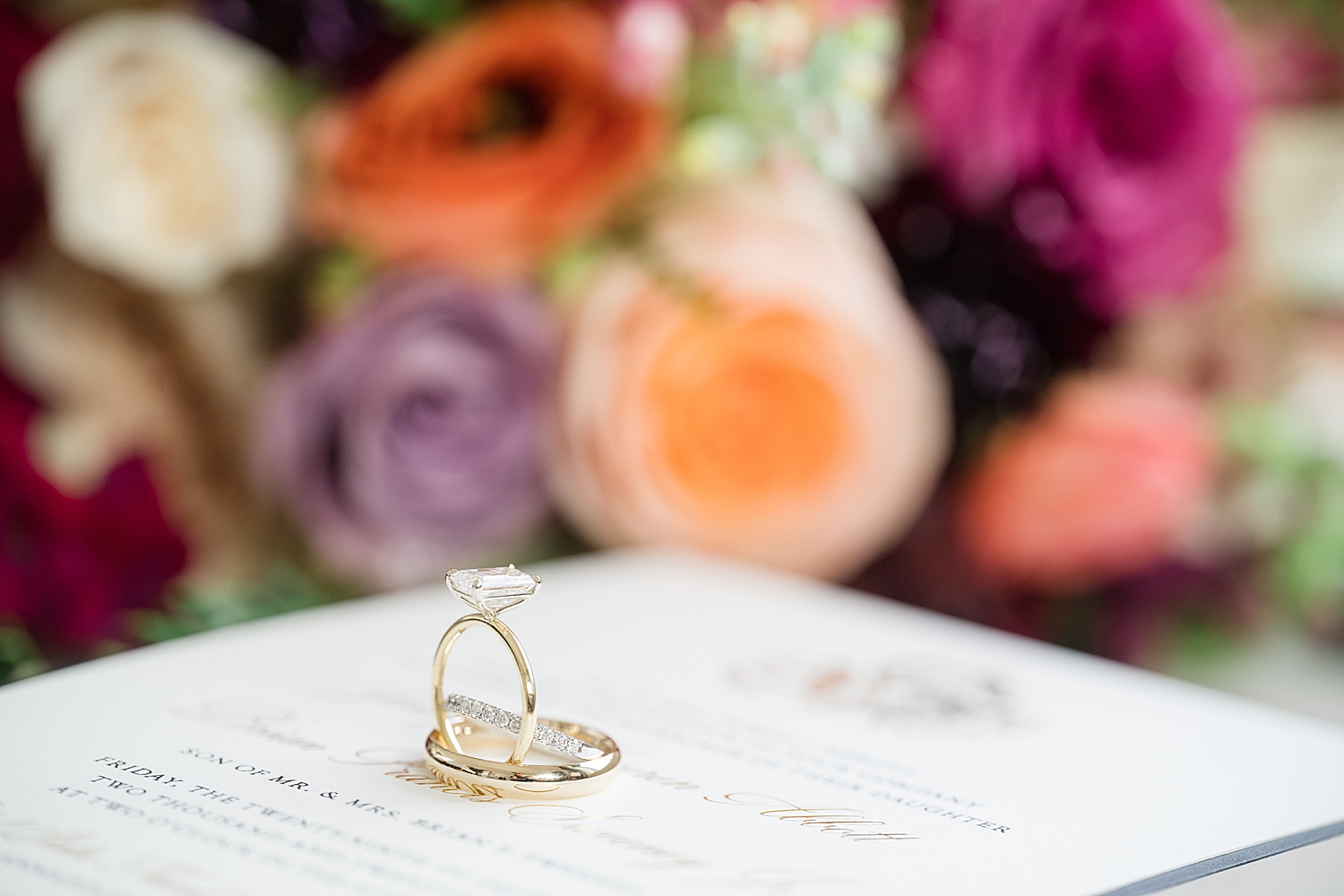 wedding rings balanced on invitation with winter florals