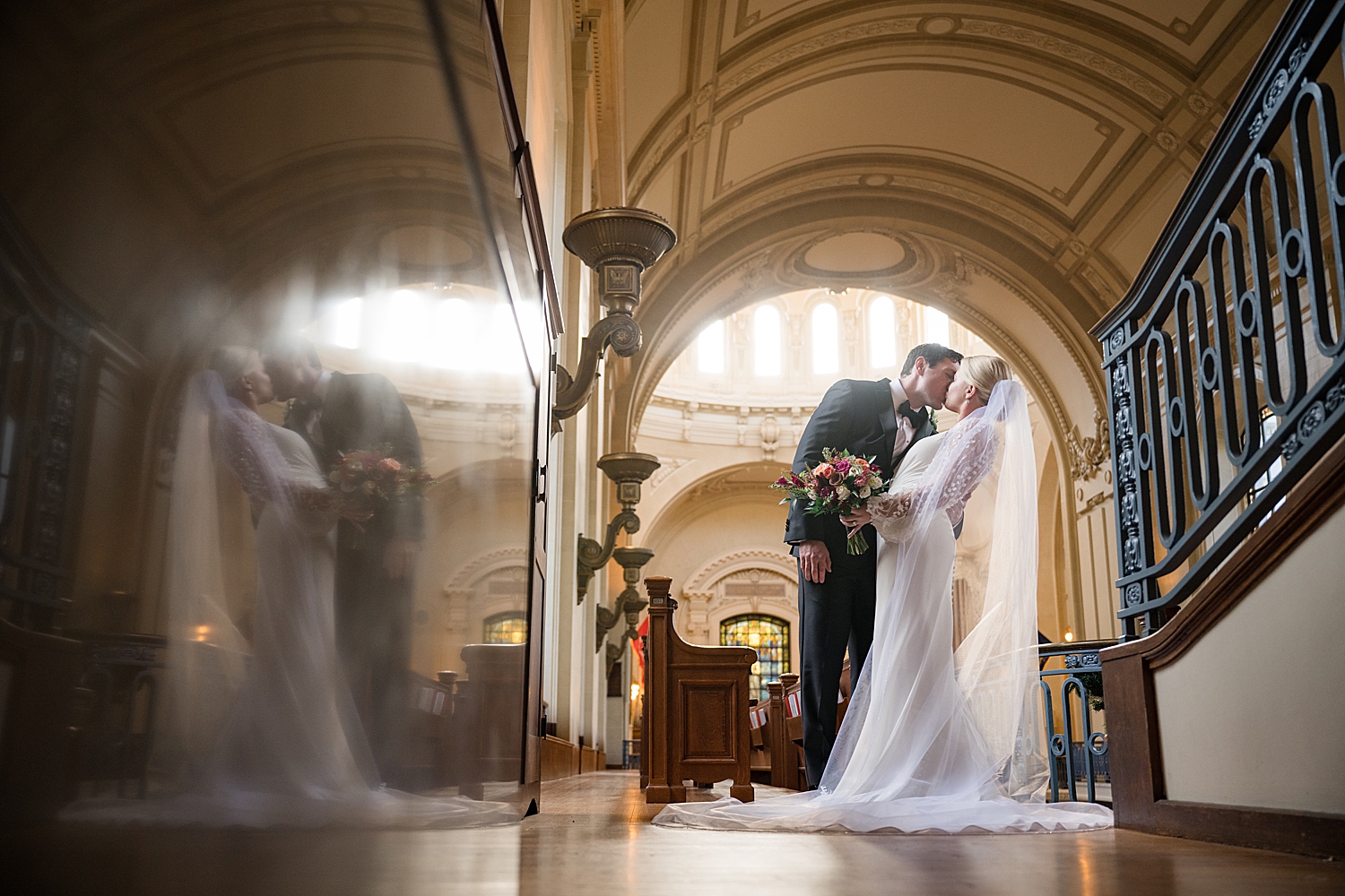 artsy wide shot with reflection of bride and groom in chapel